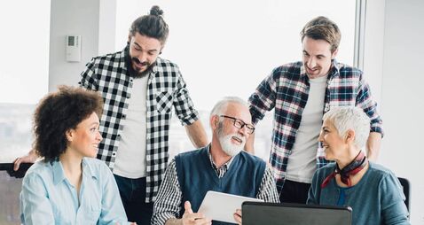 Senior business man holding tablet and having fun with coworkers