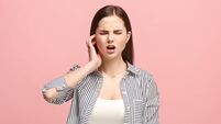 The Ear ache. The sad woman with headache or pain on a pink studio background