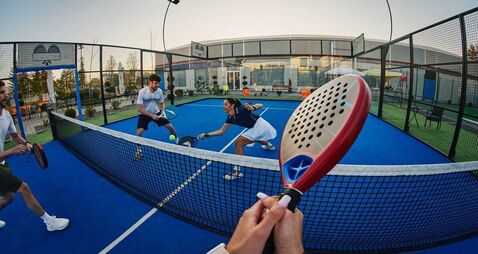 Friends playing padel on a blue outdoor court — energetic POV shot of group sport and recreation