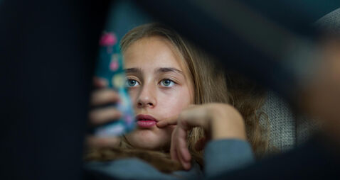 F2KT0J Young girl relax with her smartphone on a sofa