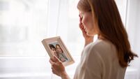 Young woman crying holding picture frame remembering husband