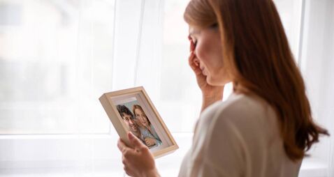 Young woman crying holding picture frame remembering husband