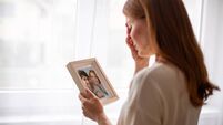 Young woman crying holding picture frame remembering husband