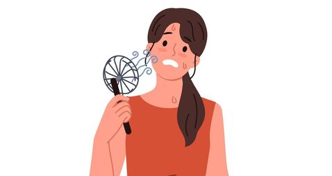Woman uses electric fan to stop sweating and prevent exhaustion in hot summer weather
