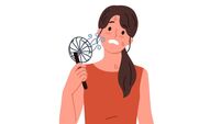 Woman uses electric fan to stop sweating and prevent exhaustion in hot summer weather