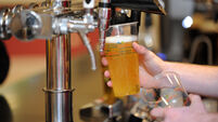 A girl pulls a pint of beer / lager in a pub.