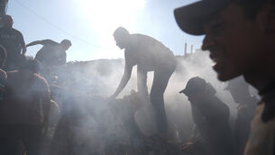 People near a destroyed vehicle in Gaza City (Jehad Alshrafi/AP)