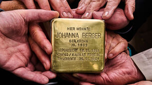 Relatives pose for a photograph holding a palm-sized brass Holocaust plaque (Markus Schreiber/AP)