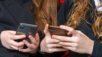 teenage school girls being cyber bullies  or just catching up on social media both on there phones, hand level  copy space above