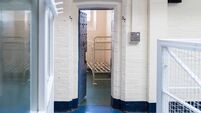 Looking in prison cell block victorian British English jail house with bed in room lock up high security room derelict old new c