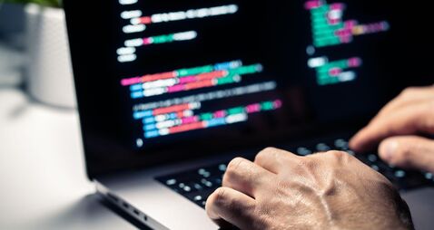 Hacker with malware code in computer screen. Cybersecurity, privacy or cyber attack. Programmer or fraud criminal writing virus
