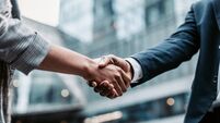 Meeting success. Two business persons shaking hands standing outside