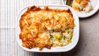 Top view of chicken and leek filo pastry pot pie. Homemade food. Light beige table background.
