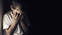 Depressed crying little boy holding head in hands