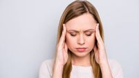 iStock-975697826 (1).jpg Portrait of unhappy sad girl holding two hands on temples suffering from head ache keeping eyes closed isolated on grey backgrou