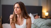 Unhappy woman sitting in bed experiencing relationship problems