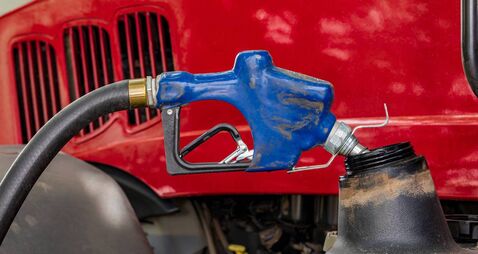 Diesel fuel nozzle fueling farm tractor. Farming input costs, fuel price increase and emissions pollution concept.