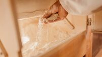 Man checking flour inside wooden grinding machine