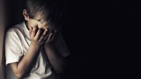 Depressed crying little boy holding head in hands