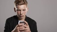 White teenage boy using mobile phone, waist up