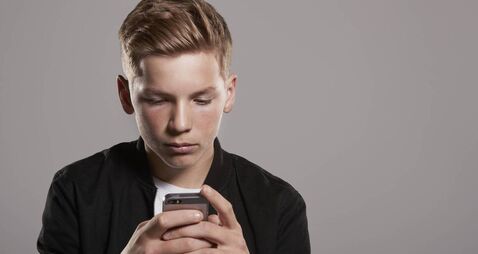 White teenage boy using mobile phone, waist up
