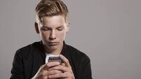 White teenage boy using mobile phone, waist up