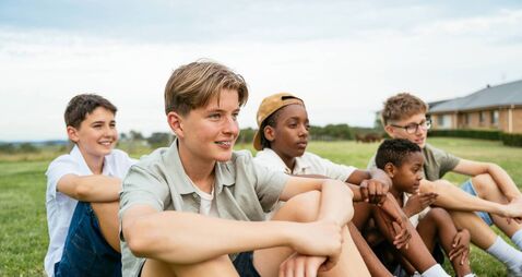 Group of Gen Z boys having fun outdoors in nature without smart phones, featured boy with acne
