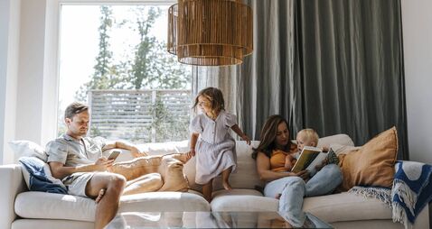 Family spending leisure time while sitting on sofa in living room at home