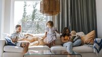 Family spending leisure time while sitting on sofa in living room at home