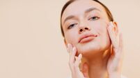 Young woman applying cosmetic white cream on her face