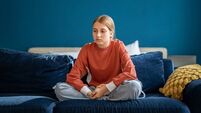 Upset teen girl sitting on sofa at home feeling lonely and frustrated