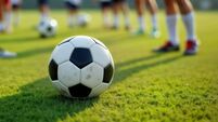 Youth soccer players practice on field. Stand in line, ready for training. Focus on black, white soccer ball. Scene shows sports