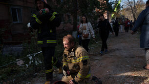 A rescue worker sits on the ground next to a residential building destroyed in a Russian missile strike on Pryluky, Ukraine (Evgeniy Maloletka/AP)