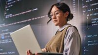iStock-2233679886.jpg Young programmer analyzing code on laptop and large screen in modern office