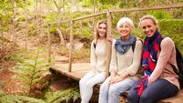 Three generations of women sitting in a forest, portrait