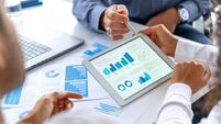 Close up of three people looking at financial data with graphs and charts.