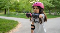 Little girl talking on a smart watch while riding roller skates