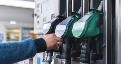 Refueling at a modern gas station with green fuel pumps and a customer filling their vehicle in a well-lit, organized space duri