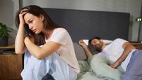 Young woman feeling sad while man sleeping in bed