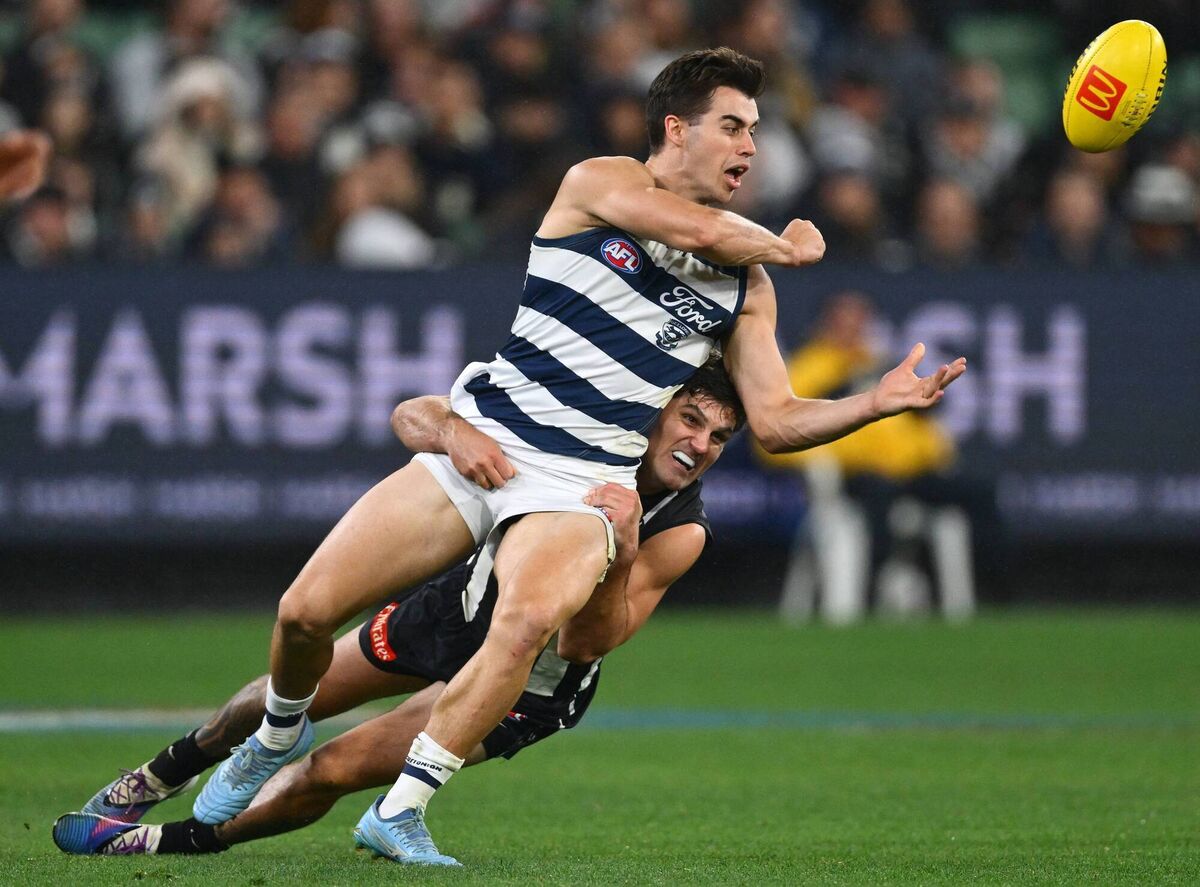 Oisin Mullin of the Cats handballs whilst being tackled by Lachie Schultz of the Magpies. Picture: Quinn Rooney/Getty Images