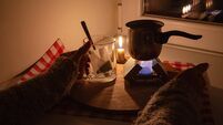 A woman boils water for tea on a small tourist stove with dry fuel in complete darkness during a power and gas outage at home. B