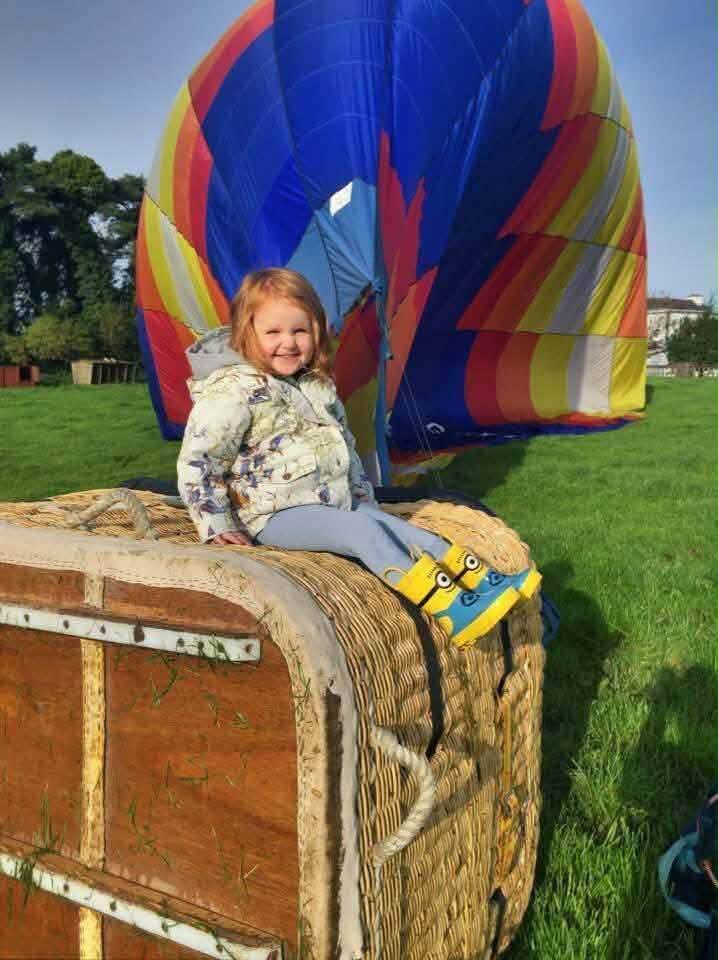 Evie Rose as a little girl posing with her father Brendan's hot air balloon.
