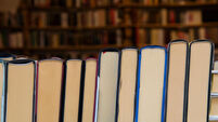 Hardcover books back edges on wooden shelves display of retail book store or shop over close up
