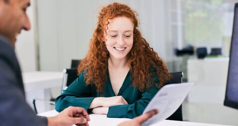 The office worker presents a document to the client across the desk.