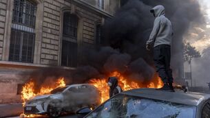<p>A protester watches a car burn at a demonstration in Paris on Saturday.</p>