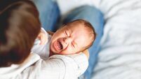 Woman holding a crying child. Mother comforts her little son or daughter.