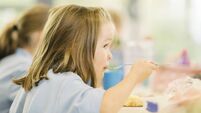 Young girl eating hot school dinner uk