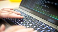 A person's hands are typing on a laptop displaying hacker code, highlighting issues of cyber security, privacy threats, and serv