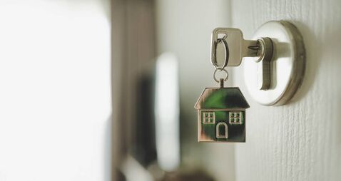 Open the door and door handle with a key and a keychain shaped house. Property investment and house mortgage financial real esta