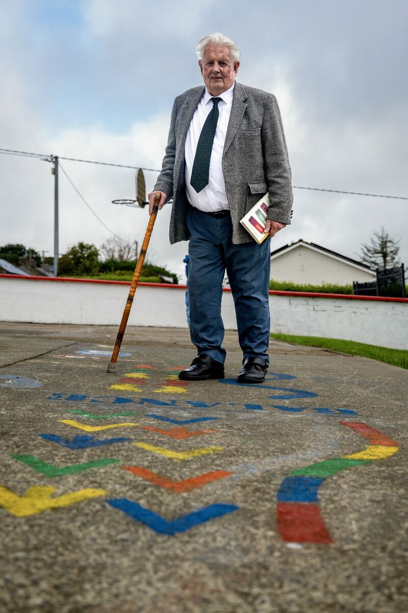 John Burke leans on his cane on a hopscotch track in the playground at Passage East National School, where he taught for more than three decades. Picture: Chani Anderson
